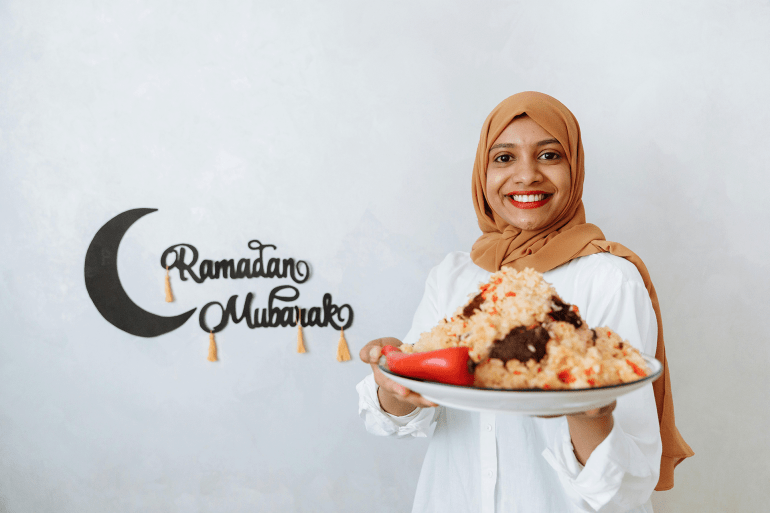 Brown hijab woman holding a plate with food